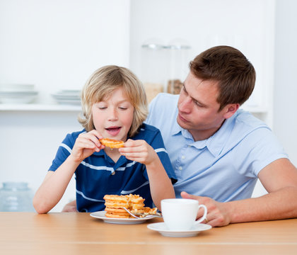Charming father and his son eating waffles