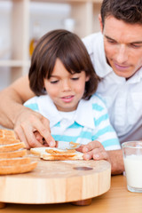 Obraz na płótnie Canvas Affectionate father and his son spreading jam on bread