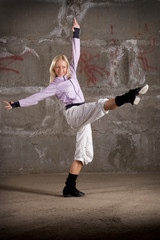 Fototapeta premium Beautiful hip hop girl dancing over grey brick wall