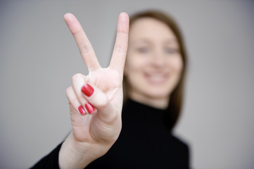 junge sympathische frau macht victory zeichen mit fingern