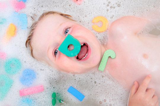 Young boy playing in bubble bath with foam letters