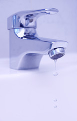 drops of water flow from faucet in bathroom