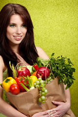 Portrait of a girl holding in hands full of different fruits and