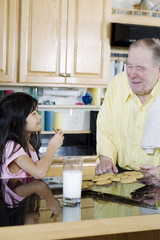 Fototapeta na wymiar Elderly man sharing cookies with granddaughter