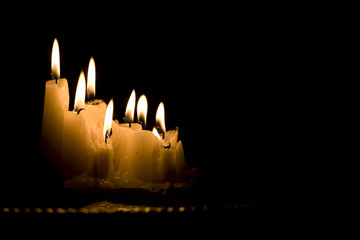 Group of white candles burning in the dark