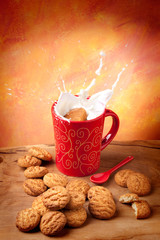 Delicious cookie falling into a cup of milk with big splash