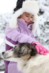 Portrait d'une petite fille caressant un chien à la neige