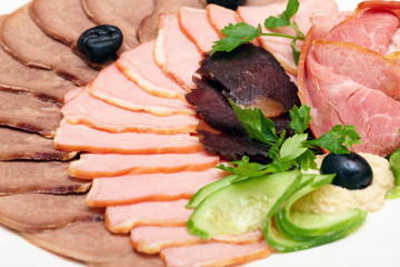 Meat assortment with cucumbers, olives and greens