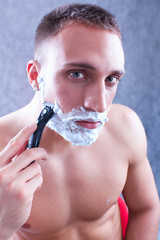 Portrait of a young man shaving his beard