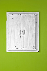 Decorative wooden door, white painted, on green wall