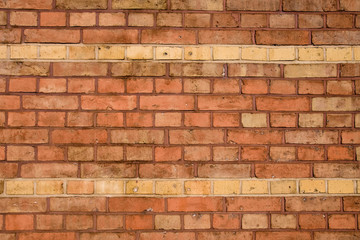 A red brick wall with two rows in ochre