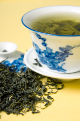 clay cup with green tea and tea leaves in dried tea leaves