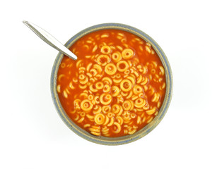 Pasta rings with tomato sauce and spoon in bowl