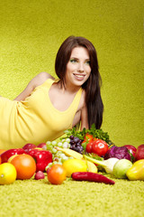 Young smiling woman with fruits and vegetables. Over green backg