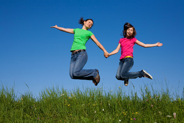 Fototapeta na wymiar Mother and daughter jumping, running against blue sky