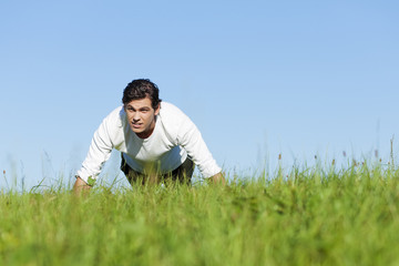 Fototapeta premium man doing push ups in summer grass