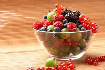 Fruit mix in the glass container, on a table from straw