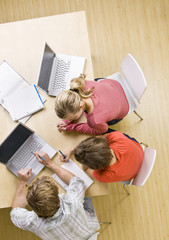 Students studying together in classroom on laptops © AVAVA