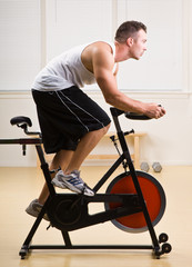 Obraz na płótnie Canvas Man riding stationary bicycle in health club