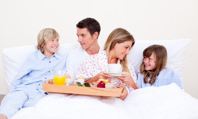 Obraz na płótnie Canvas Loving family having breakfast sitting on bed