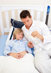 Fototapeta premium Attractive father checking his son's temperature