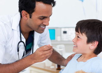 Handsome doctor giving medicine to a little boy