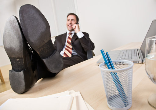 Businessman Talking On Telephone With Feet Up