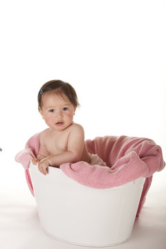 Pacific Islander baby girl sitting in white tub with attitude