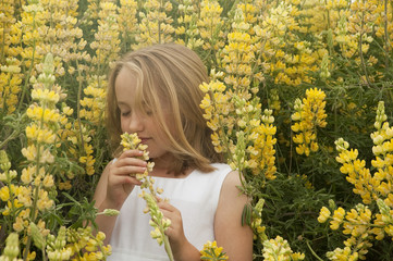 blonde little girl smelling yellow spring wildflowers