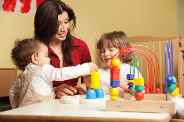 two little girls and female teacher in kindergarten