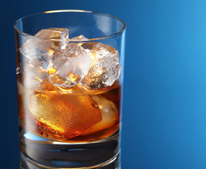 Glass of brandy with ice cubes isolated on a blue