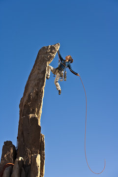 Female rock climber reaching the summit.