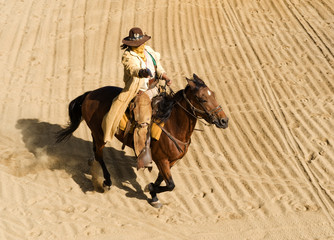 Cowboy riding a horse at full gallop shooting a gun