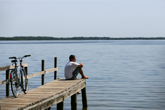 Homme assis au bord d'un lac