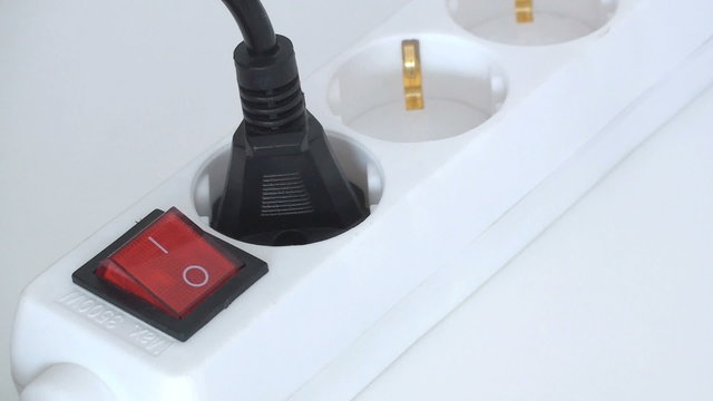 mann bet&auml;tigt den knopf einer steckerleiste