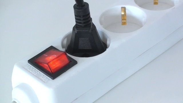 mann steckt stecker in die steckdose und bet&auml;tigt den knopf