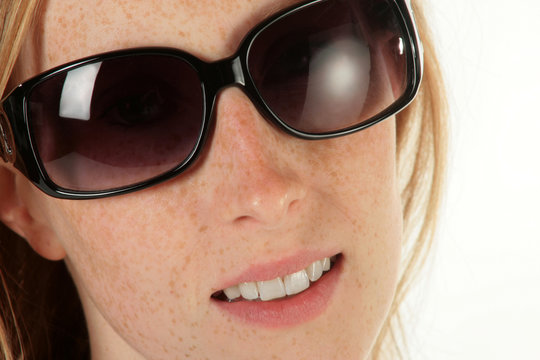 Ein Gesicht einer Frau mit Sommersprossen und Sonnenbrille