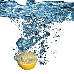 Fresh lemon dropped into water with bubbles isolated on white