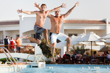 Two men jumping in swimming pool