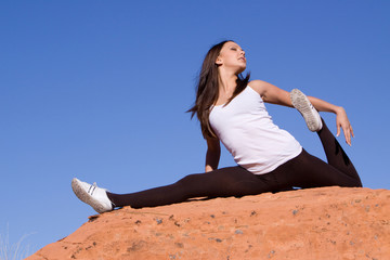 Naklejka na ściany i meble Flexible gymnast girl exercising on red rocks