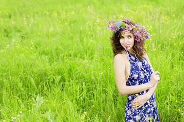 Fototapeta na wymiar Girl wearing a wreath of wild flowers in the field