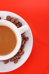 Small white cup of coffee with coffee grain on red background
