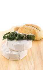 Cheese with white mold and a bundle of herbs on cutting boards