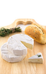 Cheese with white mold and a bundle of herbs on cutting boards