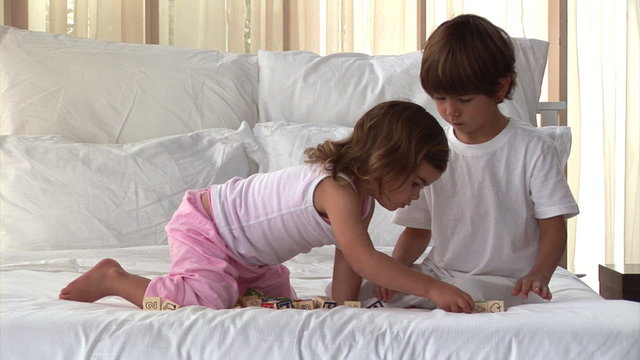 Well-behaved children playing on the bed at home