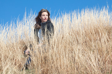 Woman looking into distance sitting in wheat