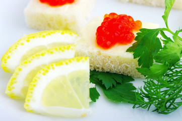 Sandwiches with red caviar and greens on a white plate