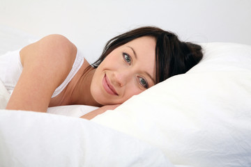 Obraz premium junge Frau liegt im Bett und lächelt
