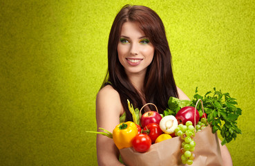 Portrait of a girl holding in hands full of different fruits and