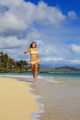 teenage girl runs along the beach at lanikai, hawaii